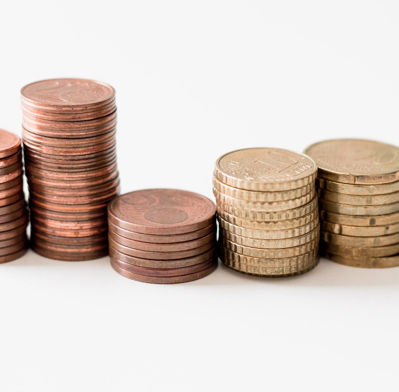 stacked round gold-colored coins on white surface